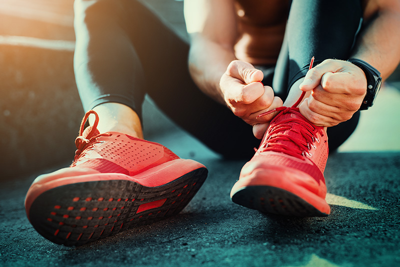 Close up of an athlete tying the laces on their bright red shoes