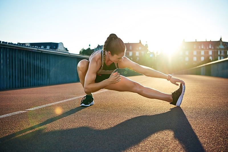 Female athlete stretches in preparation for an early morning run